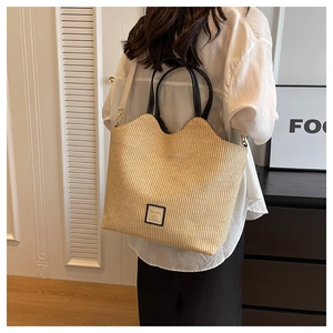 Détail du sac cabas en paille tissée avec bords ondulés et anses en cuir noir