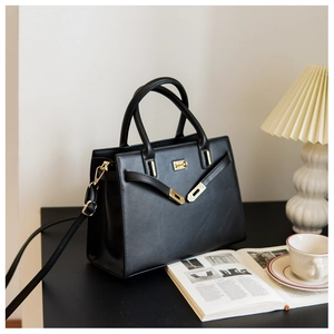 Detail of elegant black leather handbag with gold buckle in cozy office scene