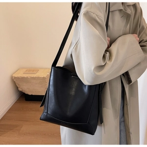 Dettaglio borsa a secchiello nera minimalista con cuciture raffinate e pelle liscia fine