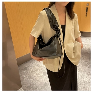 Detail of black pleated cloud bag showing soft PU leather texture and ruched shoulder strap