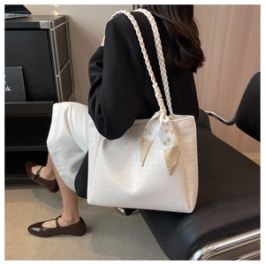 Detail of white tote bag with houndstooth embossing and floral scarf on woven strap