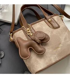 Top view of brown and beige bucket bag with cute dog charm and golden hardware detail
