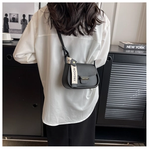 Detail view of black saddle bag with gold logo and stylish fashion letter webbing