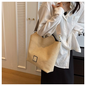 Gros plan sur un sac cabas tressé beige avec bordure marron et finition vague