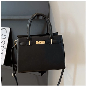 Detail of black leather handbag featuring golden metal twist lock and adjustable shoulder strap