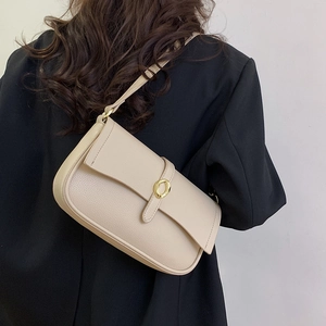 Borsa sottobraccio beige in ecopelle con fibbia dorata abbinata a una giacca nera