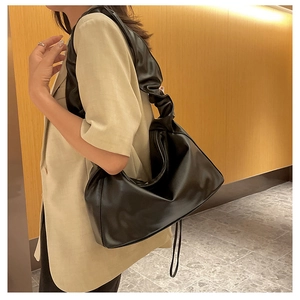 Detail view of black PU leather bucket bag featuring unique pleated drawstring strap design