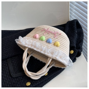 Detail of woven straw bag with colorful 3D hearts, lace trim and pink embroidery