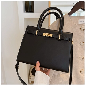 Detail view of the black textured handbag featuring gold hardware and structured design