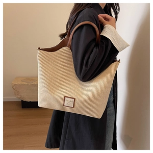 Gros plan d'un sac cabas en paille tressée avec anses en cuir marron et logo