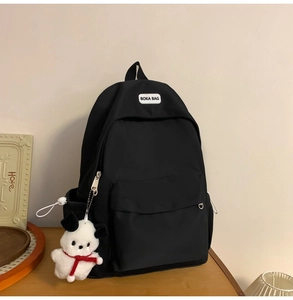 Detail of black nylon backpack with BOKA BAG label and cute puppy plush charm