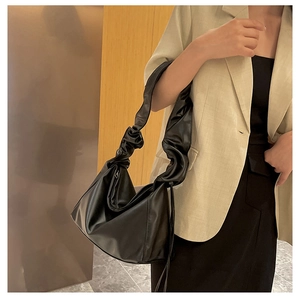Detail view of black pleated tote bag with chic scrunchie-style shoulder strap design