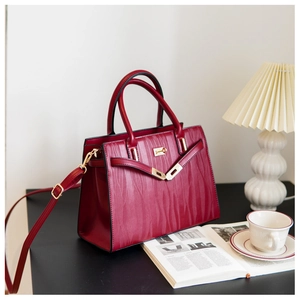 Burgundy handbag with wave pattern embossing and gold buckle in lifestyle setting