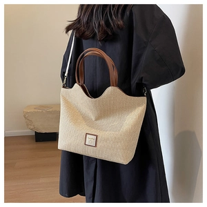 Détail du cabas tissé avec bords ondulés, poignées en cuir marron et écusson logo