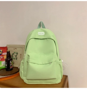 Detail of mint green nylon backpack showing front pocket and BOKA BAG logo patch