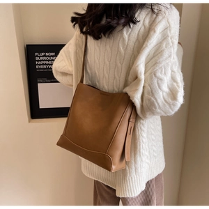 Dettaglio borsa a secchiello marrone vintage in pelle con cuciture e tracolla sottile