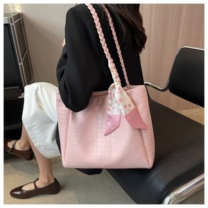Close-up of pink houndstooth tote with woven rope strap and cherry print silk scarf detail