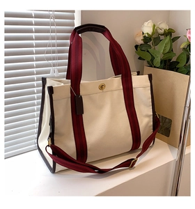 Detail of canvas tote bag with burgundy straps and golden twist lock closure