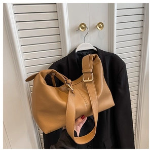 Close-up of caramel faux leather texture and golden metal buckle on shoulder bag
