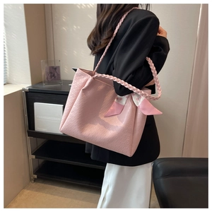 Detail of light pink tote bag featuring embossed patterns and braided shoulder strap