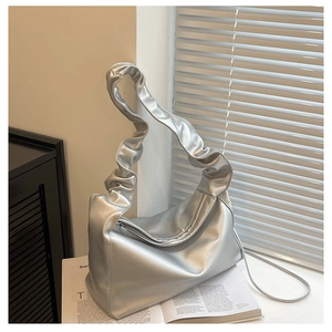 Detail of silver metallic textured bucket bag featuring a ruffled pleat shoulder strap