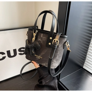 Detail of grey denim bucket bag with black leather handle and cute puppy charm