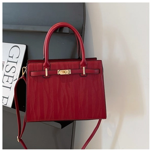 Detail of red embossed leather handbag with metal buckle and wavy texture finish