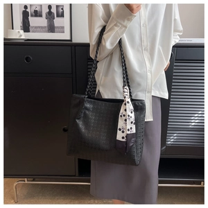 Close-up of black tote bag featuring a woven grid texture and stylish decorative scarf