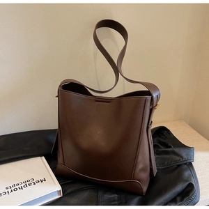 Dettaglio di una borsa a secchiello in pelle marrone scuro con rivetti in metallo