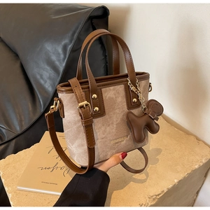 Detail of vintage canvas and brown leather crossbody bucket bag with puppy charm
