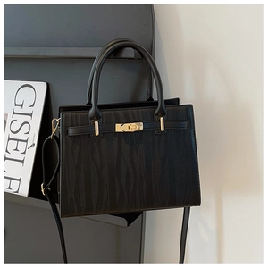 Black leather handbag with textured pleats and golden metal twist lock on a display rack