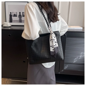 Detail of black houndstooth tote bag with woven strap and decorative scarf accent