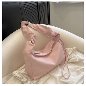 Detail of light pink hobo bag featuring ruched strap and stylish side drawstring tassel
