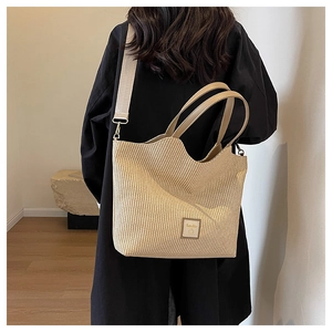 Détail du sac cabas en paille tissée avec bord ondulé et écusson logo en tenue décontractée