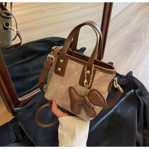 Detail of khaki canvas and brown leather bucket bag with a cute 3D dog pendant