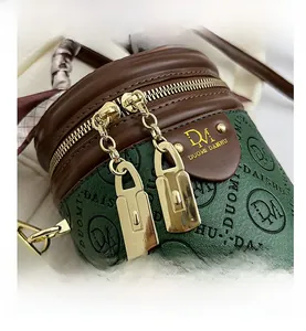 Detail der grünen Leder-Beuteltasche mit Logo-Prägung und goldenem Doppelreißverschluss
