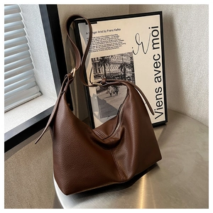 Detail of dark brown lychee leather texture and silver zipper on large dumpling bag