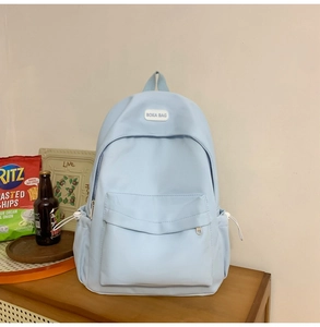 Detail of light blue waterproof nylon backpack with zipper pocket and side drawstring pocket