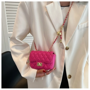 Detail of rose red quilted crossbody bag with gold chain and decorative gold ball