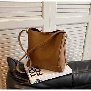 Dettaglio ravvicinato della borsa a secchiello in pelle marrone su un libro bianco elegante