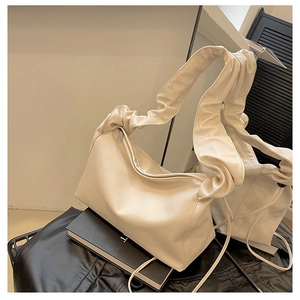 Detail of cream shoulder bag featuring pleated ruffle strap and premium matte leather finish