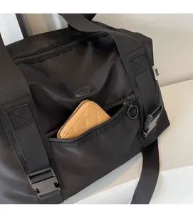 Gros plan du sac de voyage en nylon noir avec poche latérale fonctionnelle, boucle et fermeture