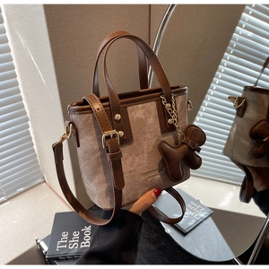 Handheld view of a vintage mini bucket bag with canvas stitching and dog charm