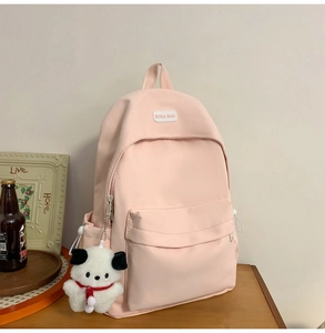 Pink canvas backpack detail with a front zipper pocket and a cute white puppy plush charm