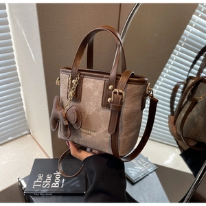 Close-up of taupe canvas bucket bag with brown leather handles and a puppy charm