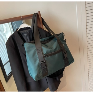 Détail d'un sac de voyage en nylon vert avec poignées sangles et boucle sur porte-manteau