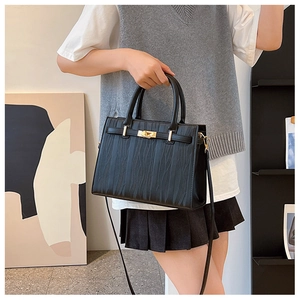 Detail of black wave-textured leather handbag with gold metal lock and dual top handles