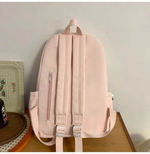Detail of pink canvas backpack back featuring anti-theft zipper pocket and padded straps