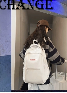Detail view of white nylon backpack featuring red Ruikeda embroidery and side buckles