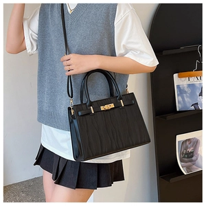 Detail of black wave pattern leather handbag with golden twist lock and top handle